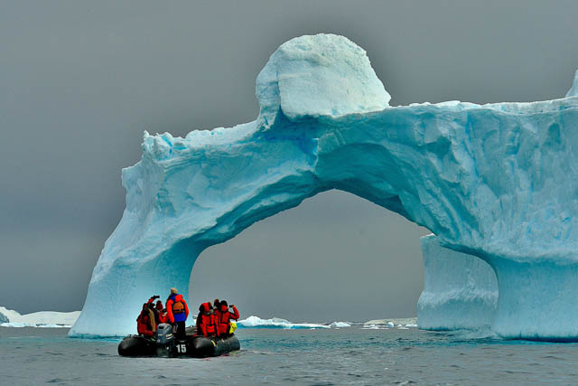travellers crossing under an ice structure on a raft in falkland island