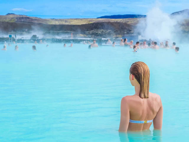 woman takes a dip at hot springs in blue lagoon iceland