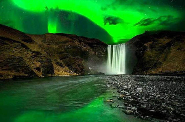 polar lights flashing above skogafoss waterfalls iceland